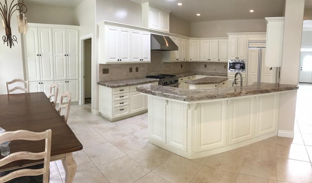 Cream-colored kitchen with granite countertops, stainless steel appliances, and a central island.