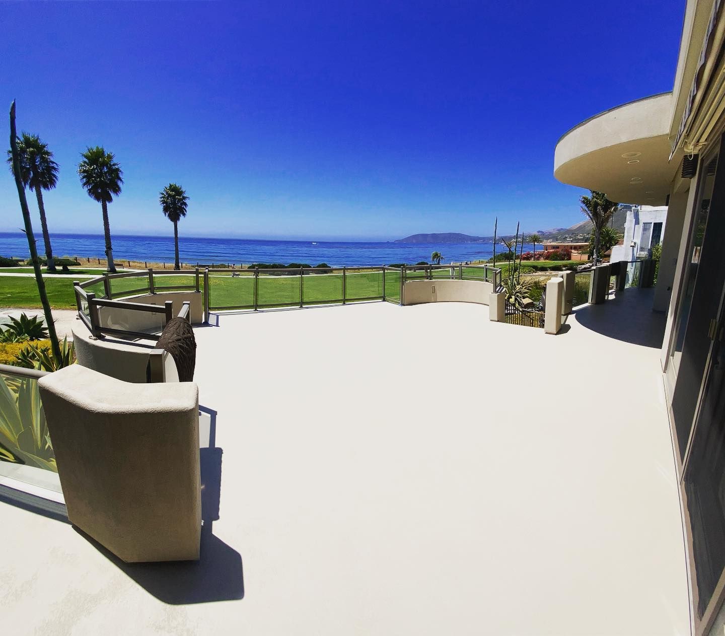 A coastal patio overlooks the ocean under a clear blue sky.
