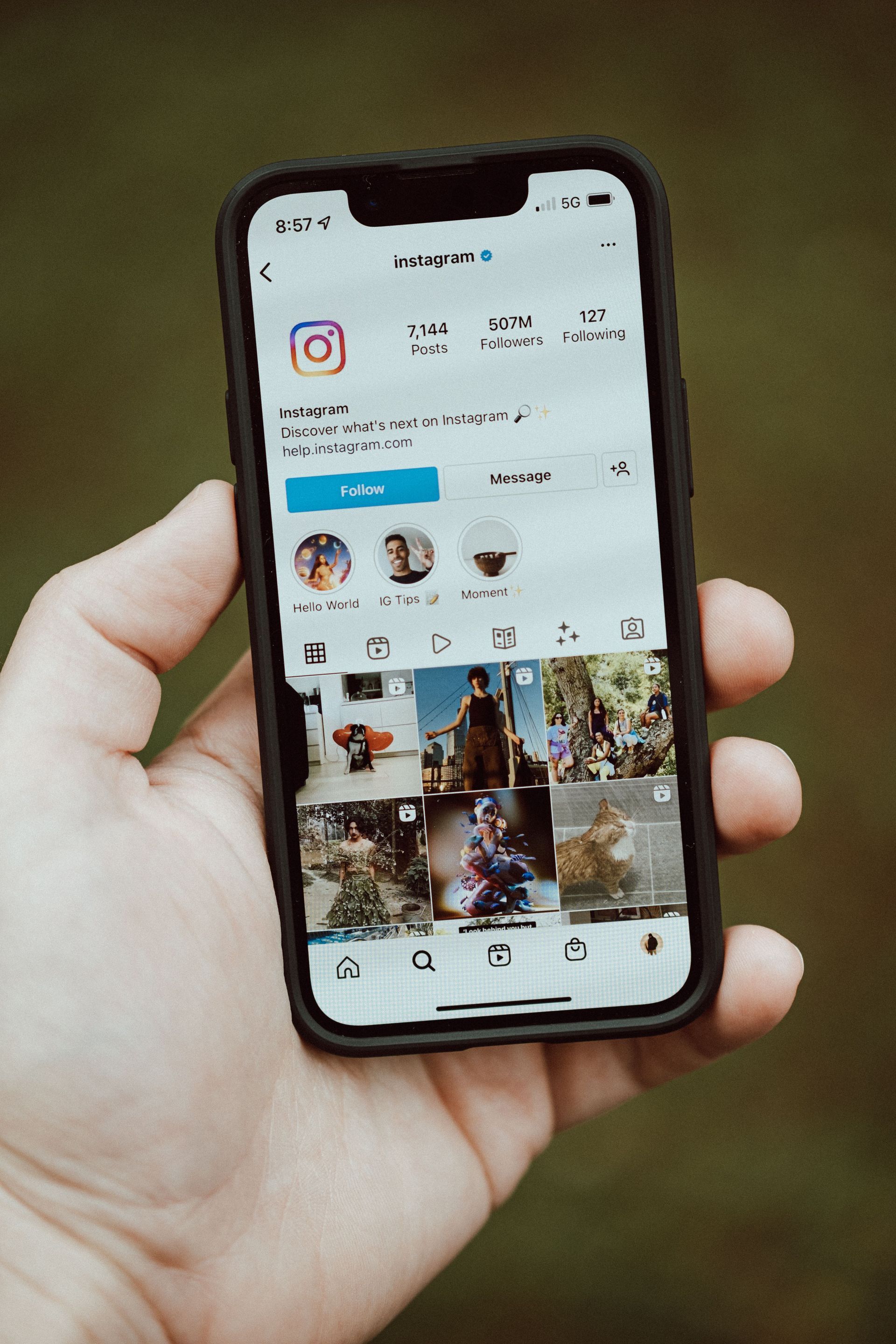 Hand holding a smartphone showing an Instagram profile page on the screen.