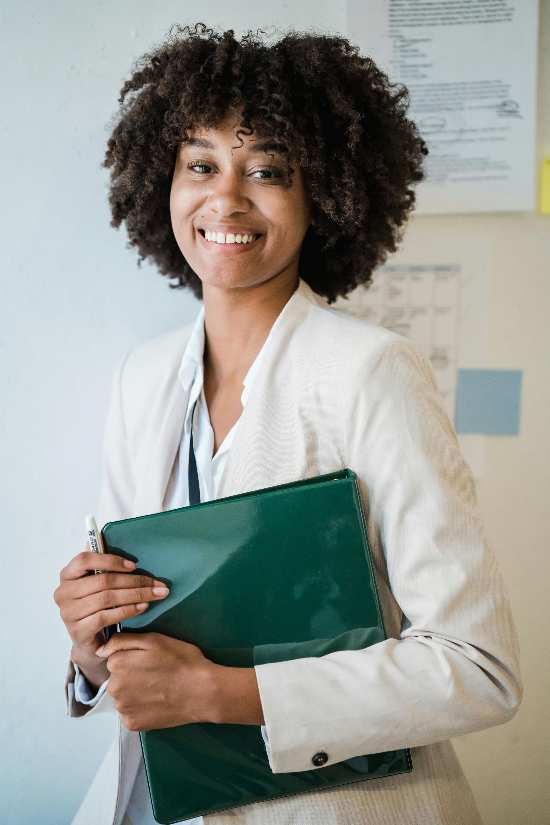 Smiling professional holding a green folder in an office setting
