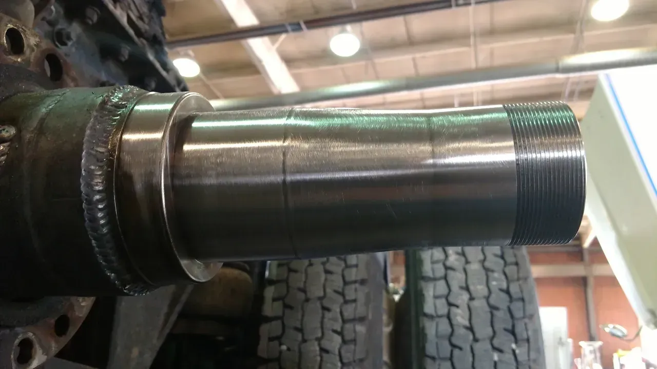 A large metal cylinder is sitting on top of a tire in a garage.