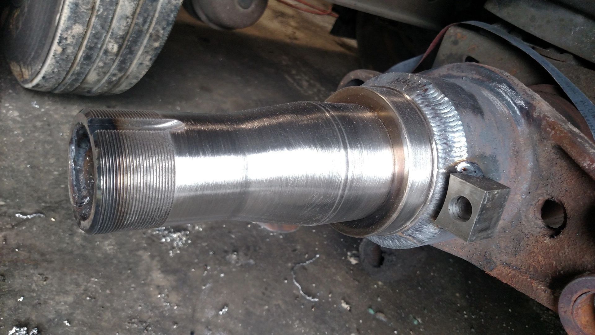 A close up of a metal object on the ground next to a tire.