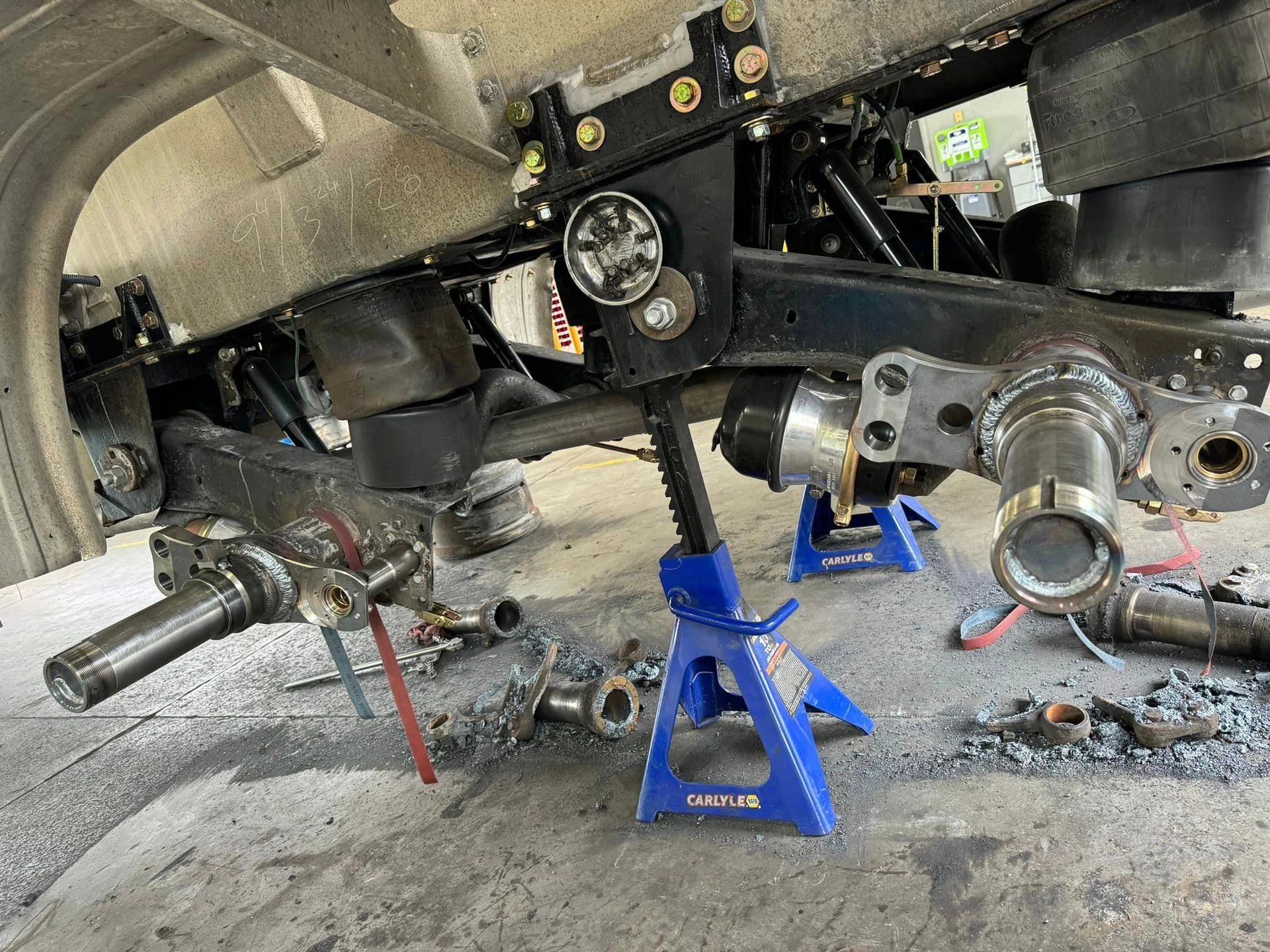 A car is being worked on in a garage with blue jack stands.