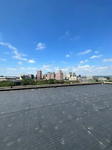 Rooftop view of a city skyline under a blue sky with scattered clouds