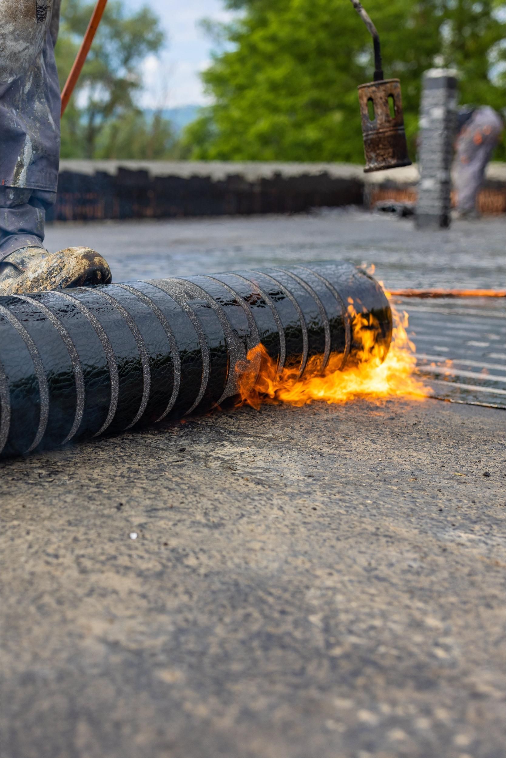 Black hose or cable on pavement with orange flames and smoke near a road construction site