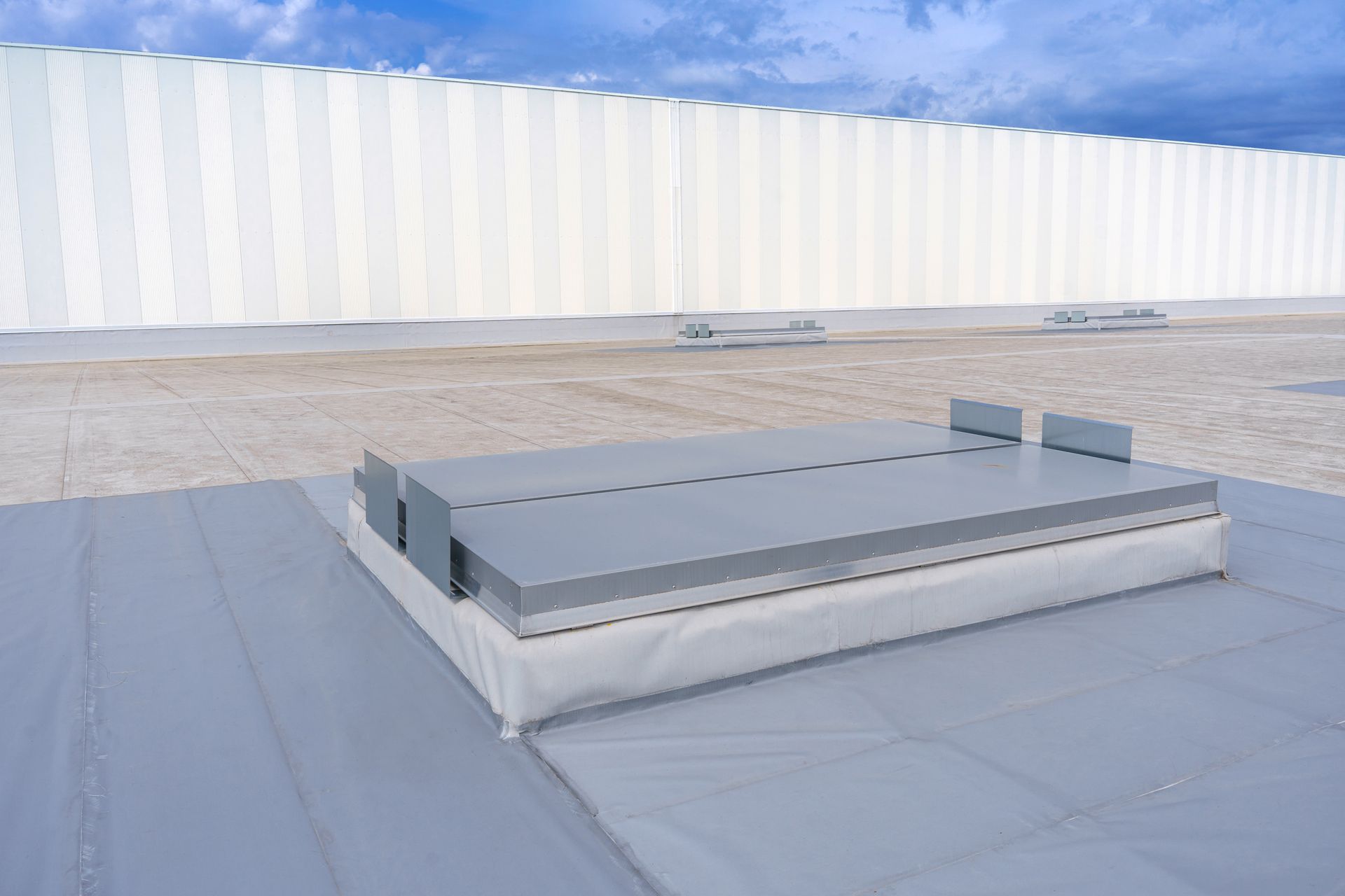 Low rooftop platform with gray panels on a white roof under a clear sky