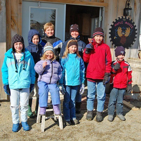 Group of children in winter jackets outside a building with a 