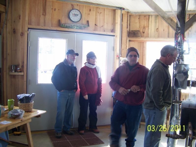 People inside a wooden building near a door; one man is operating equipment.