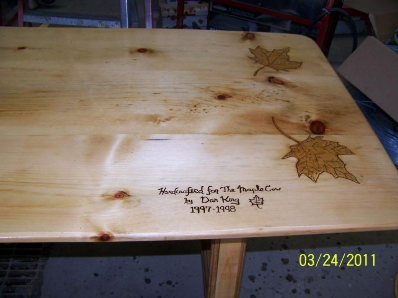 Wooden table with engraved maple leaves and text: 