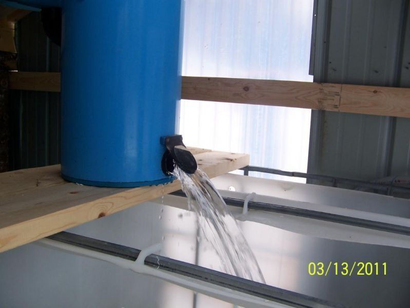 Water flowing from a blue cylinder into a white container. The date 03/13/2011 is visible.