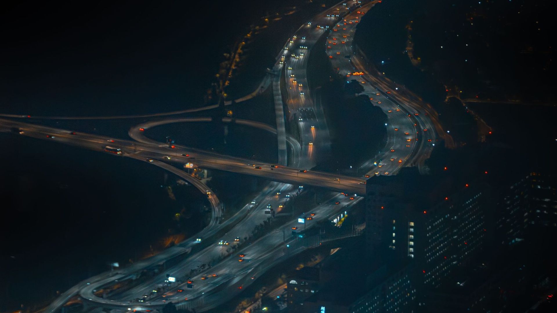 A freeway interchange at night seen from above, lanes lit end to end