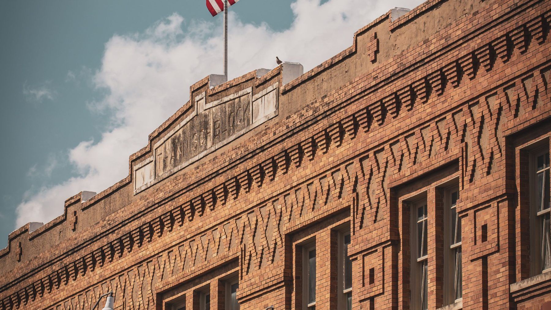 A brick storefront block and a United States flag in an old Texas downtown