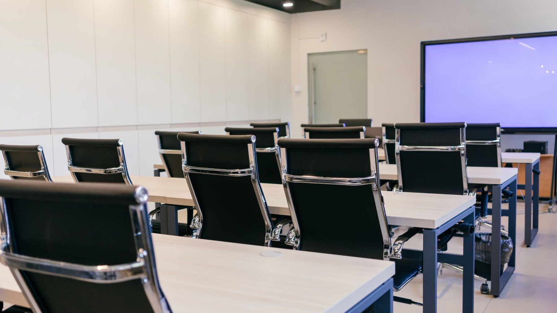 An empty meeting room with chairs set along a table