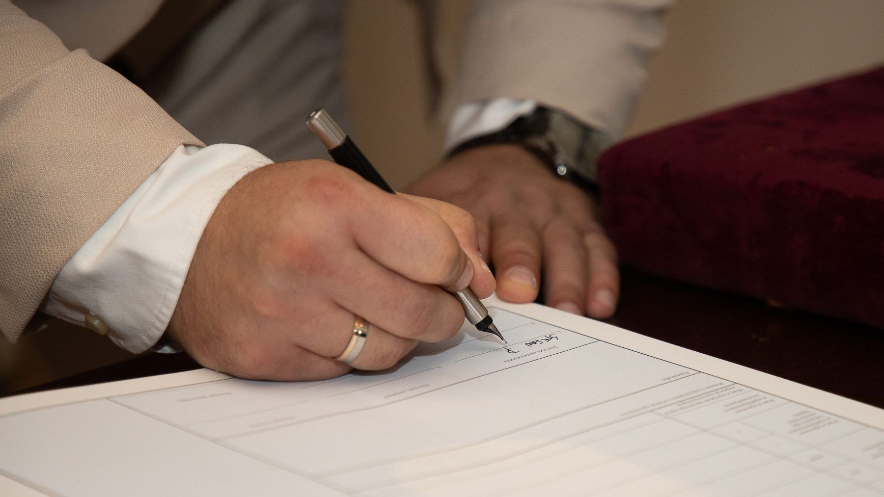 Hands signing a document across a table