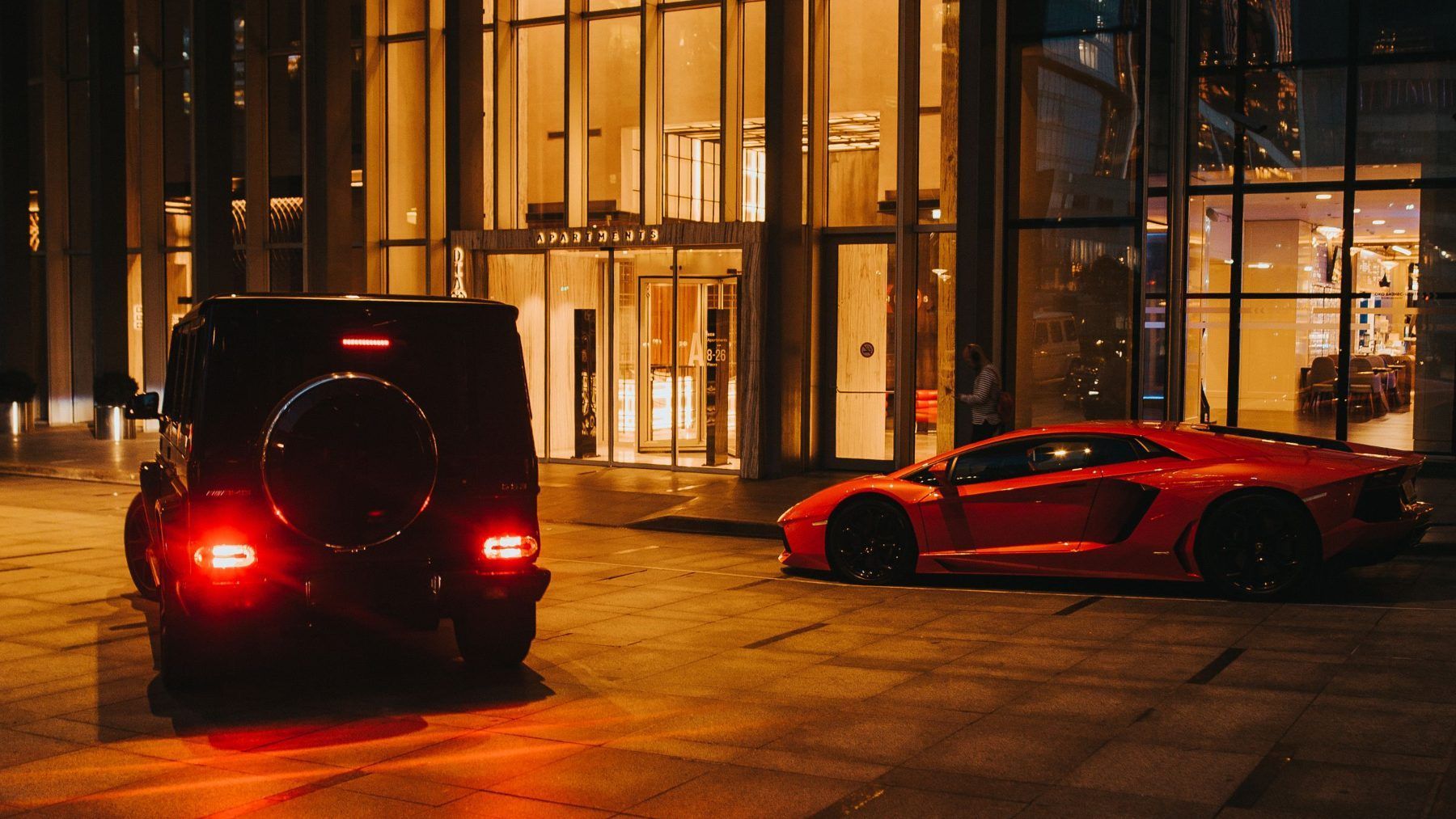 Cars waiting at a lit building entrance at night
