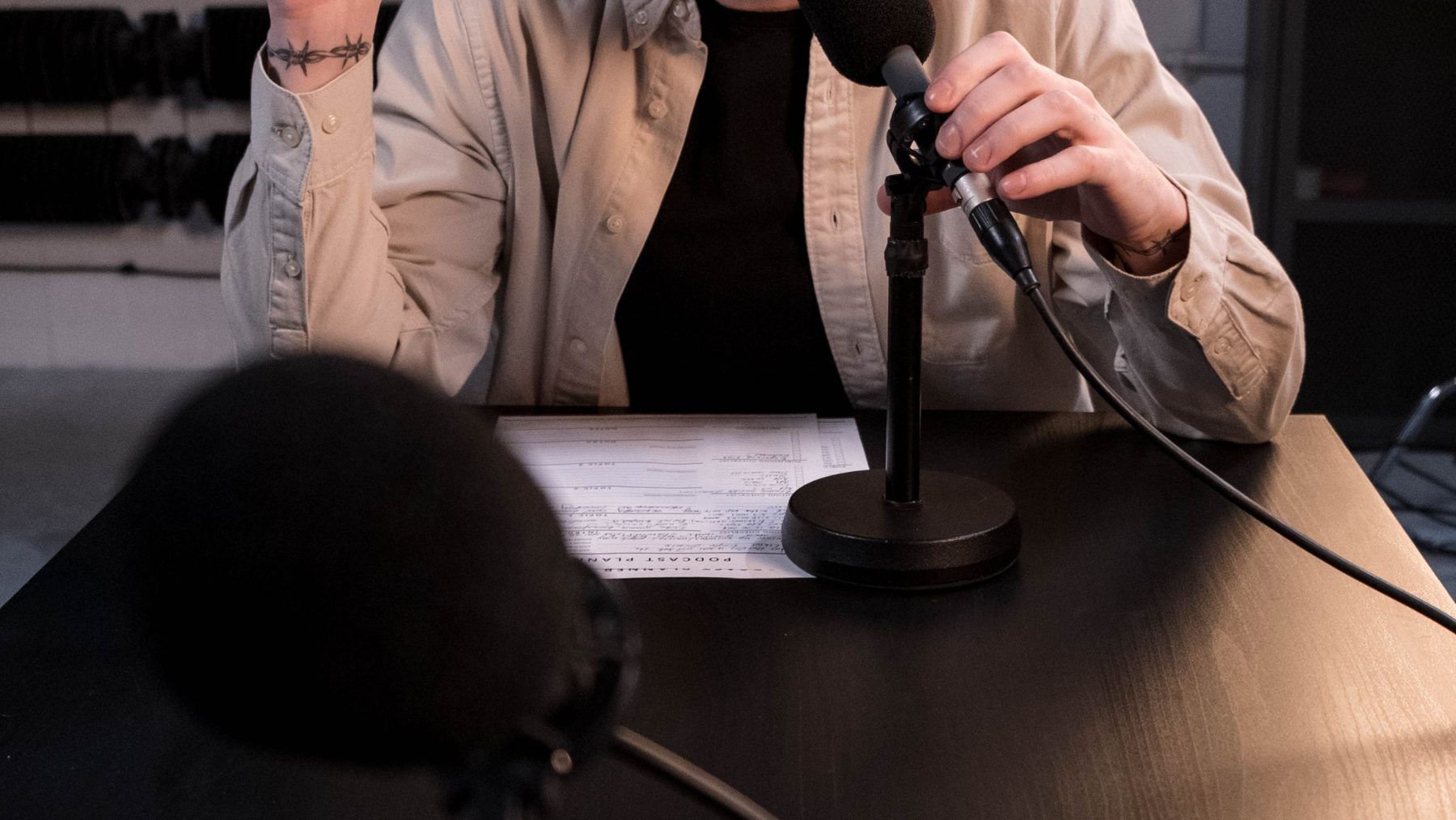Hands at a microphone on a table with notes in front of them