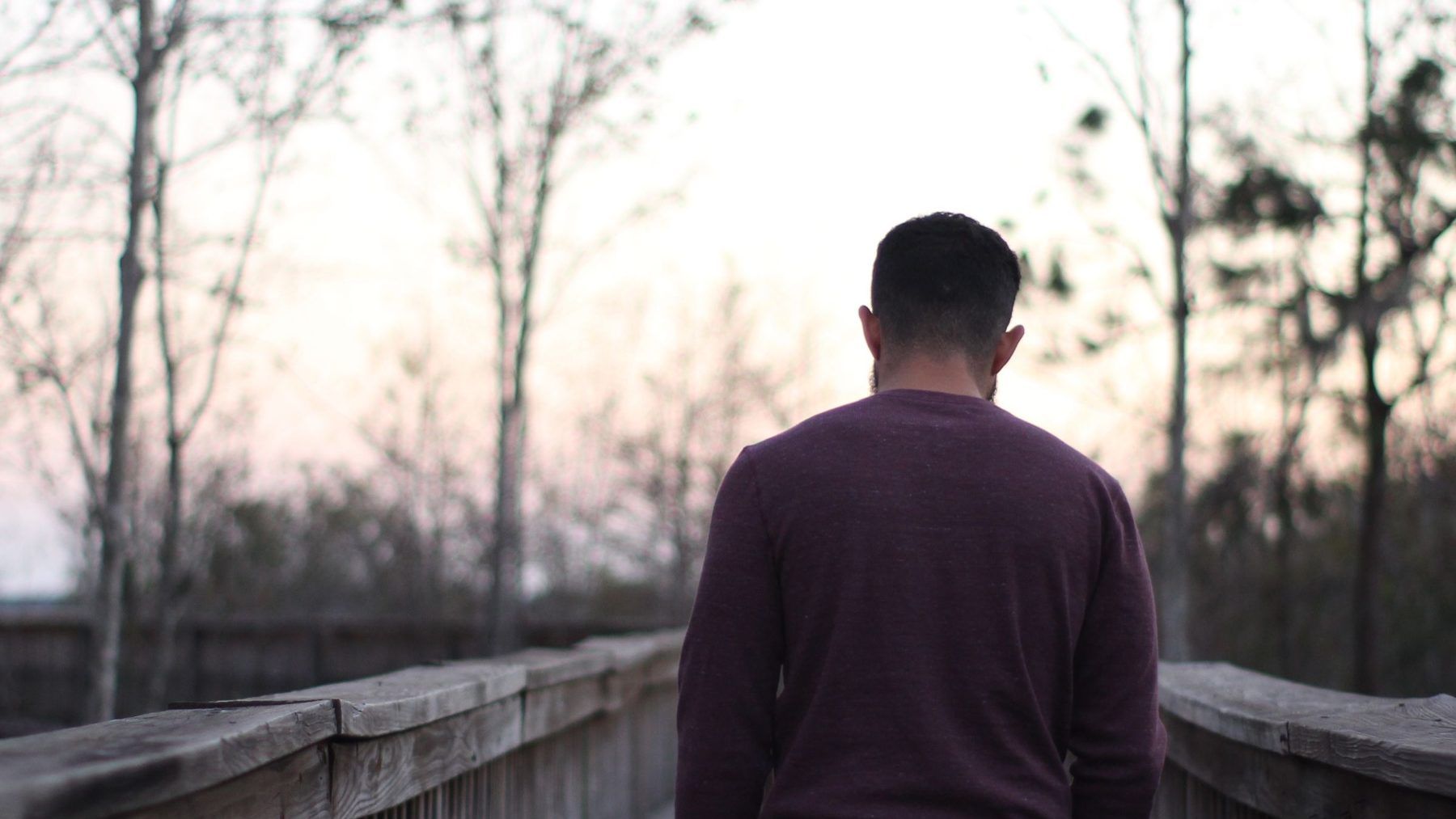 A person walking away along a bridge at dusk