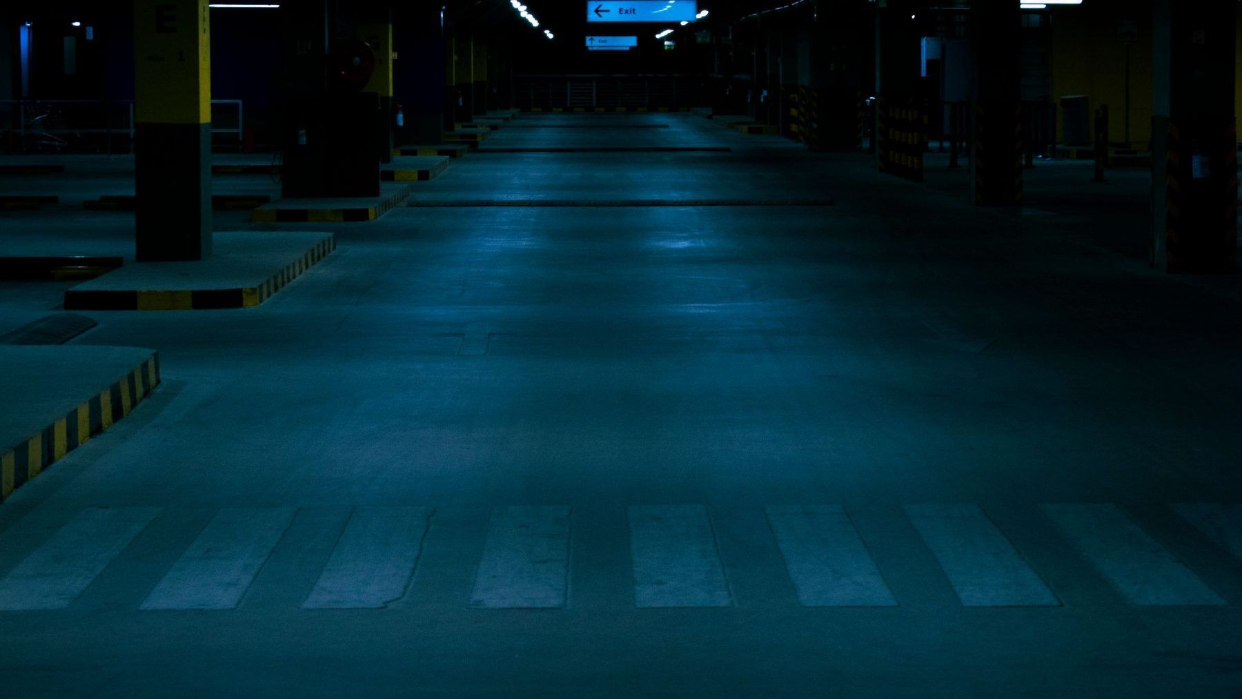 An empty underground parking garage lit end to end at night