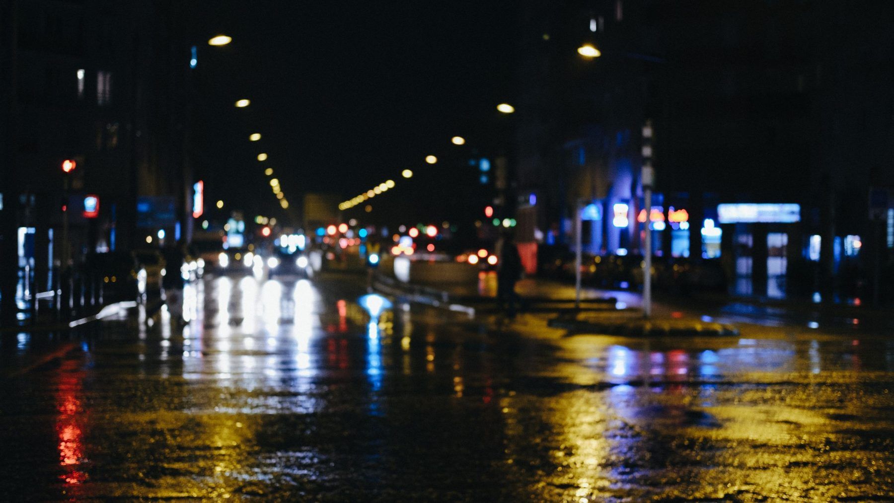 A wet city street at night with lights reflected across the road