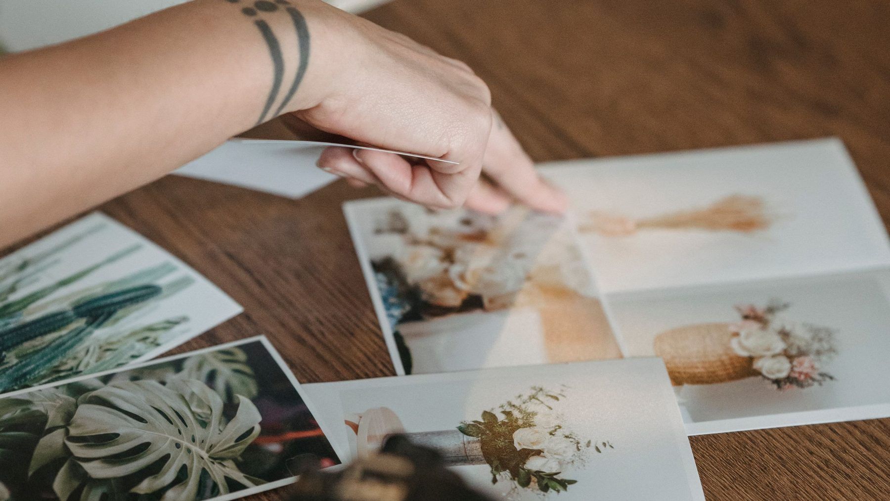 A hand laying out printed photographs across a table