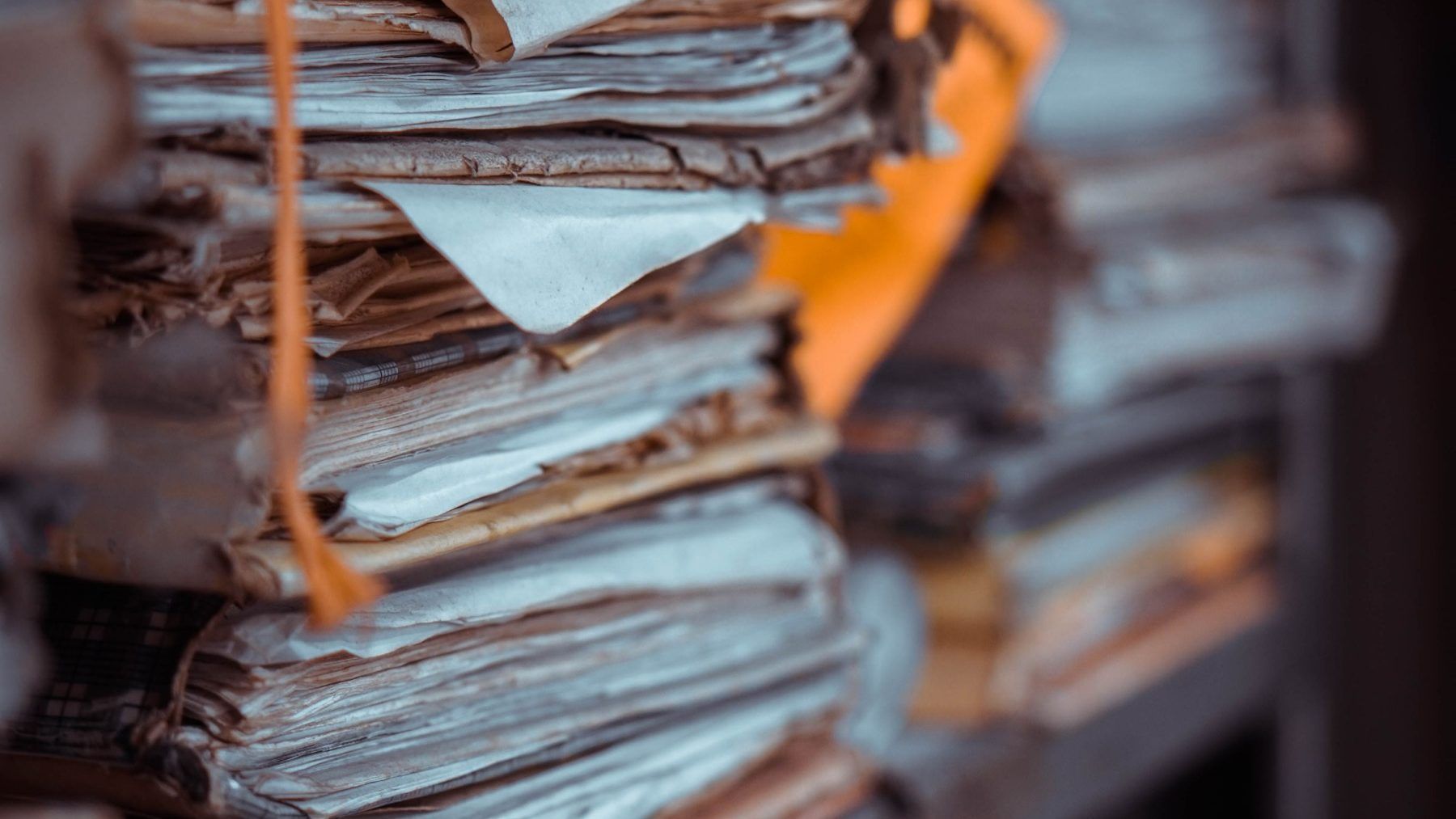 Bundles of archived paper files stacked on a shelf