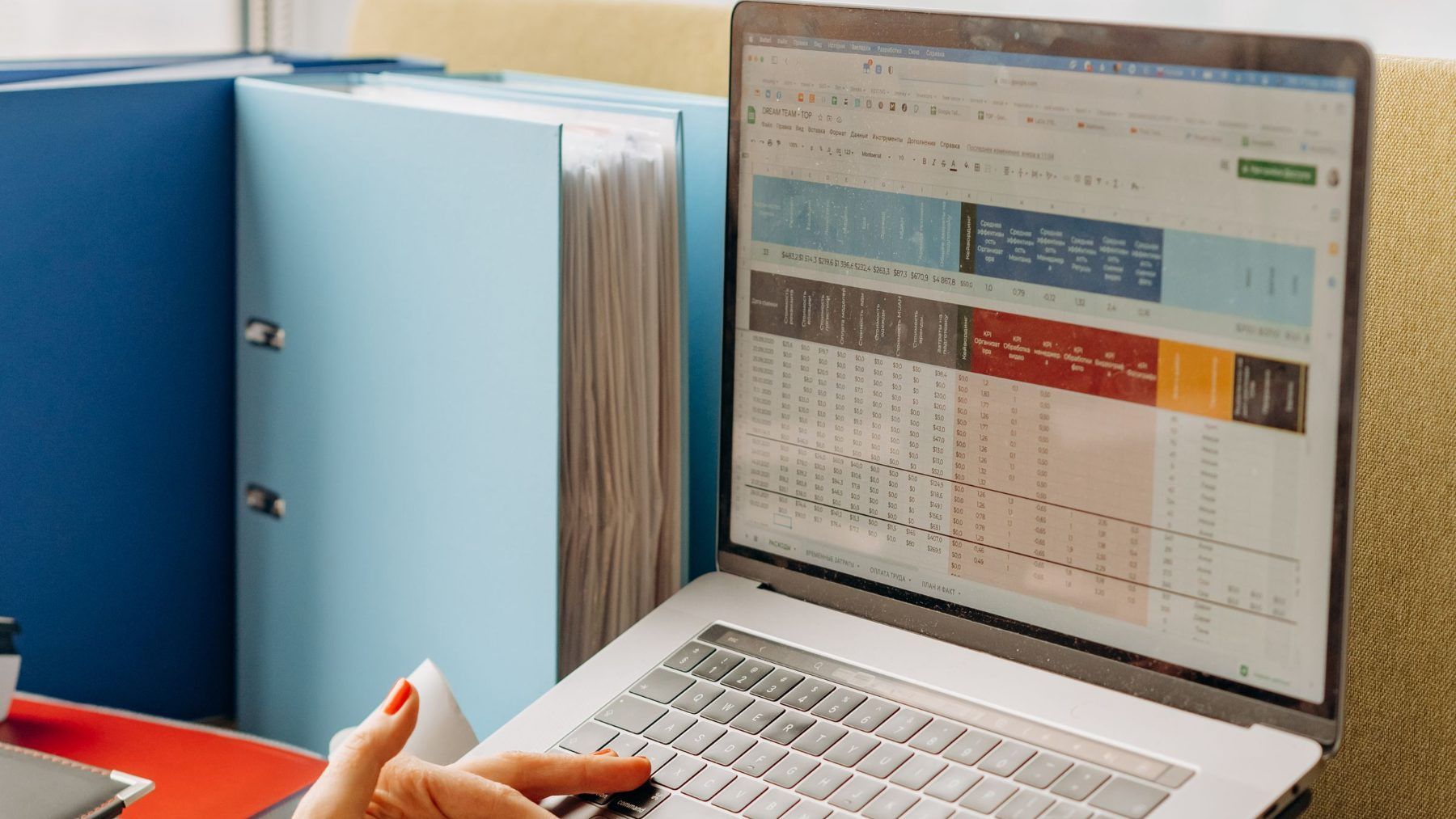 A laptop showing a spreadsheet beside a row of ring binders