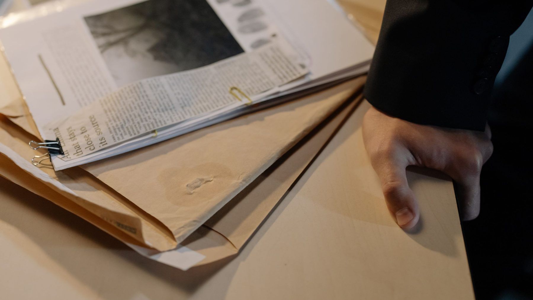 Hands going through an old file of newspaper clippings and documents