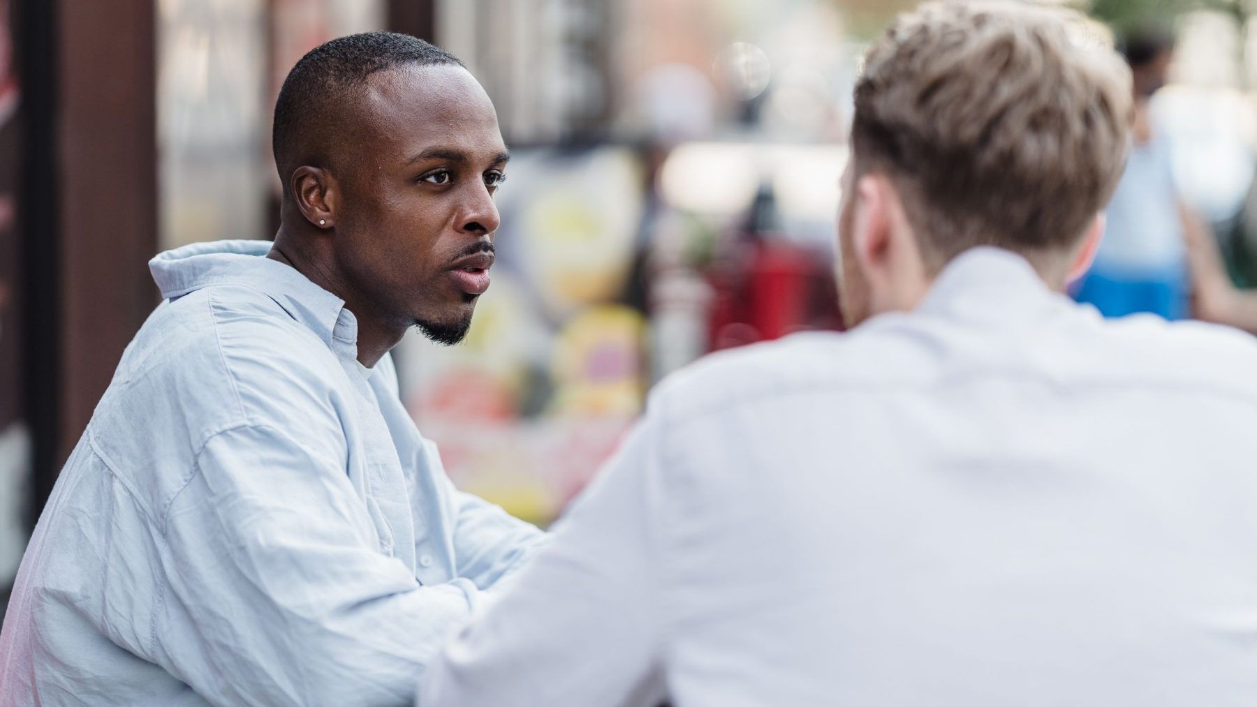 Two people sitting side by side in conversation, one listening closely