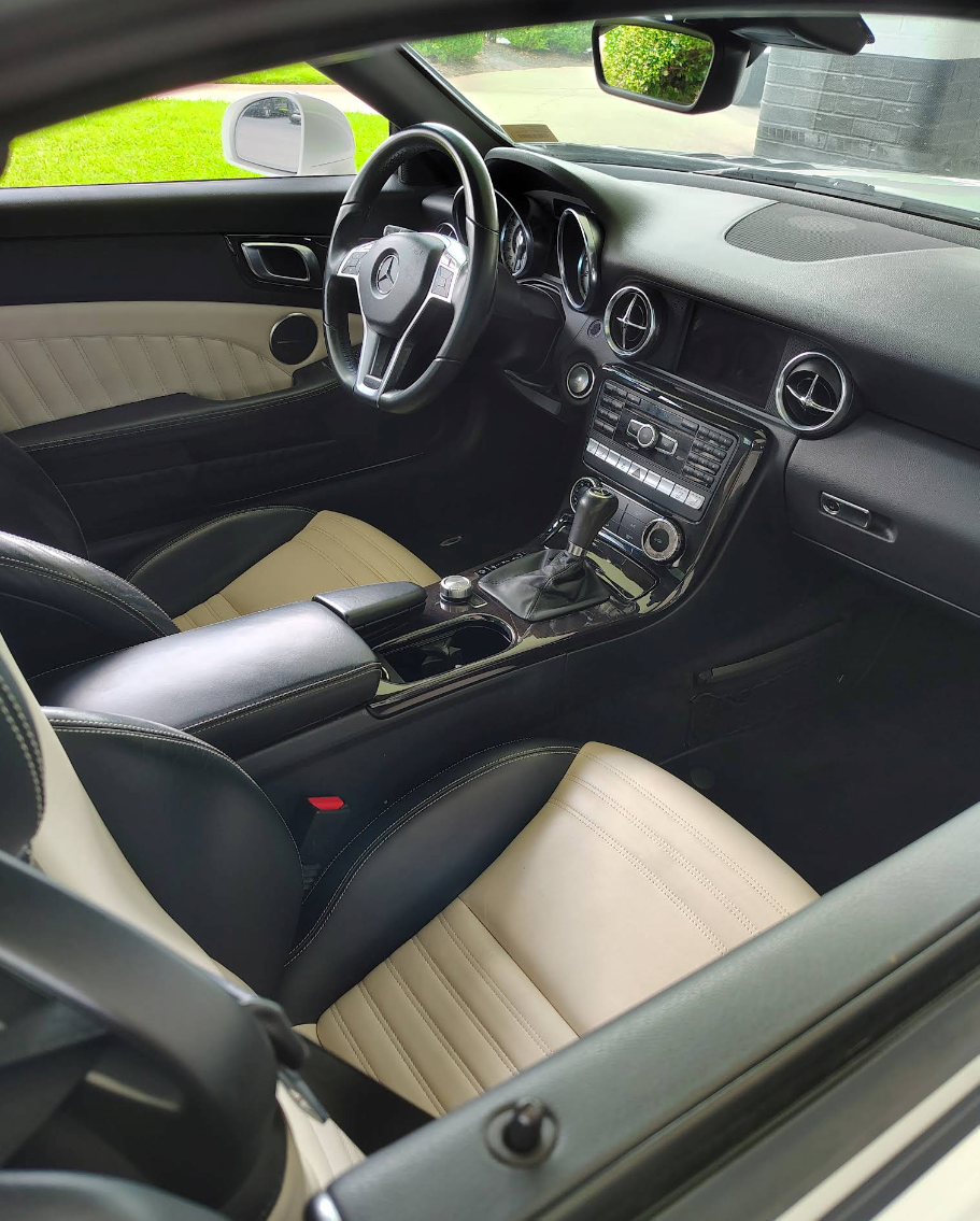 Two-tone car interior with black dashboard, beige seats, and steering wheel viewed from the passenger side | Mike's Garage