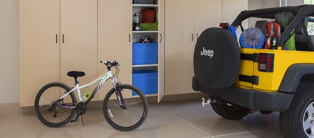 A bicycle is parked next to a jeep in a garage.