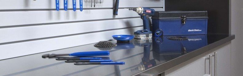 A stainless steel workbench with tools and a drill on it.
