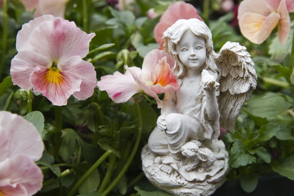 Angel statuary surrounded by blooming flowers