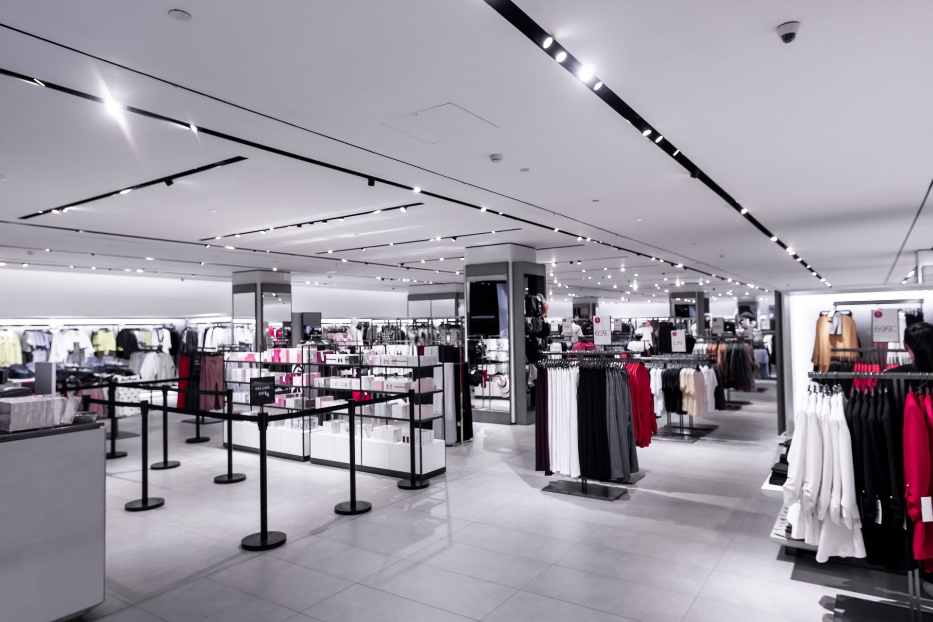 Int&eacute;rieur d'un magasin de v&ecirc;tements avec &eacute;clairage LED lin&eacute;aire au plafond et luminaires encastr&eacute;s.