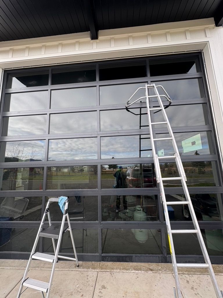 Ladders leaning against a large garage door under a building awning.
