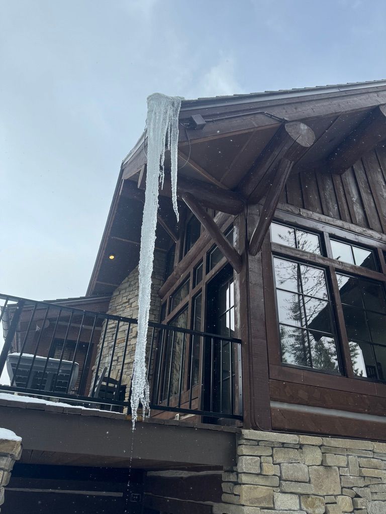 Icicles hanging from a wooden mountain lodge roof above stone siding
