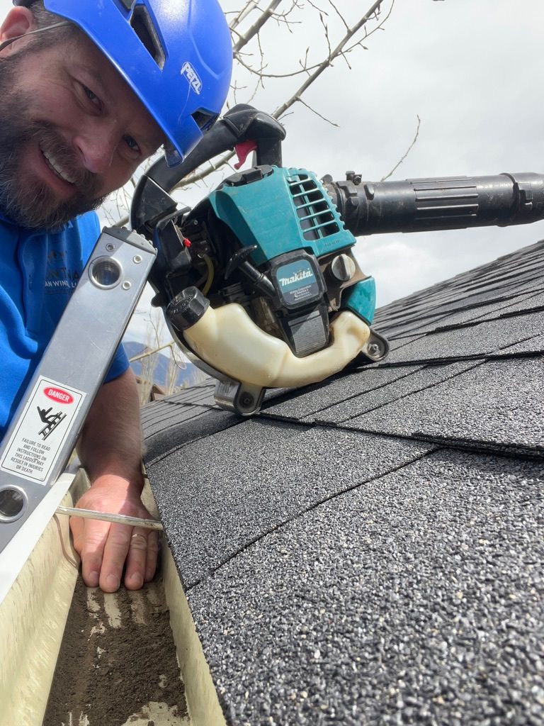 Worker in blue helmet repairing a roof with a chainsaw-like tool.
