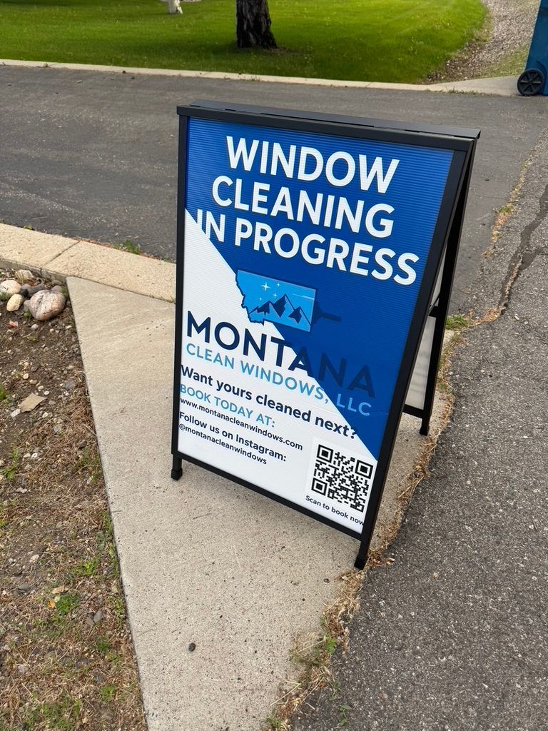 Blue sidewalk sign reading “Window Cleaning in Progress” on a residential driveway; Motion Cleaning logo visible.