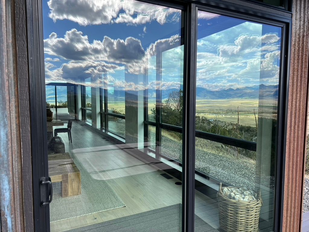 Balcony with glass railing and mountain view reflected in a sliding glass door