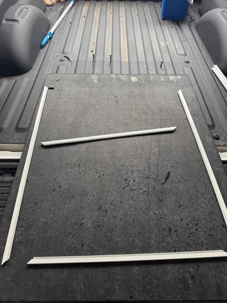 Carpeted vehicle ramp with white edge rails inside a van, with a blue tool at the back.