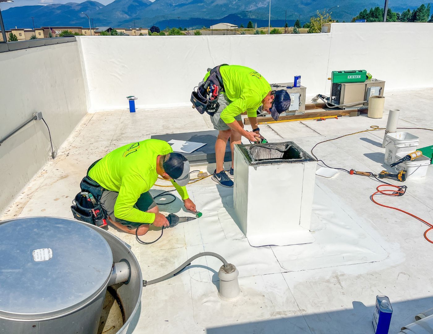 Commercial roofer diagnosing membrane damage and leak conditions on a low-slope roof in Western Montana