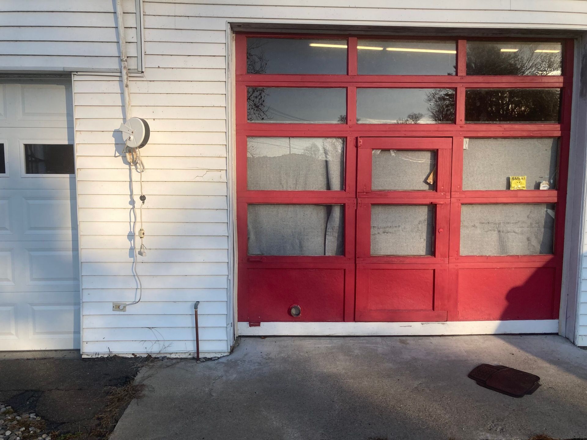 Red garage door with windows on a white house exterior, beside a gray side door and concrete driveway