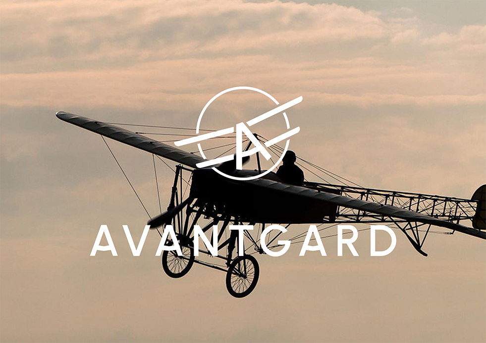 Logo vintage dvojplošníku se slovem „AVANTGARD“ na pozadí zatažené oblohy