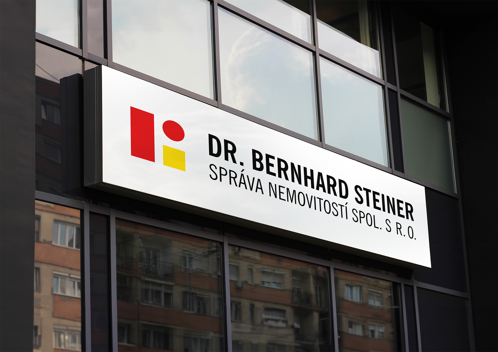 Značka kliniky Dr. Bernharda Steinera s červenožlutým logem na fasádě budovy