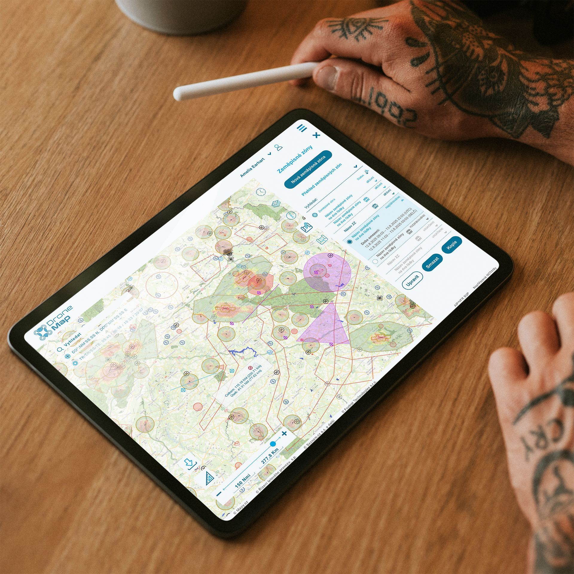 Ruce používající aplikaci s mapou na tabletu na dřevěném stole, s perem poblíž.