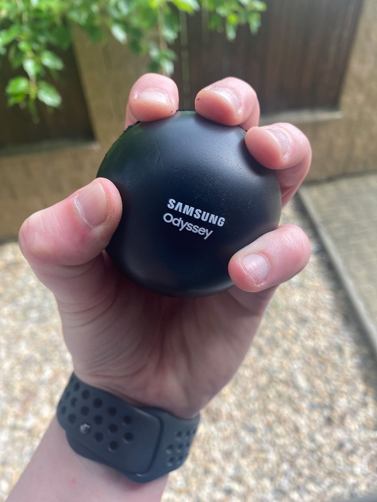 Ruka držící venku černé zařízení Samsung Galaxy s tmavým náramkem.