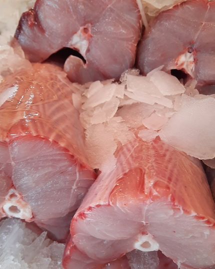 Filetes de pescado crudo sobre hielo picado en un puesto del mercado.