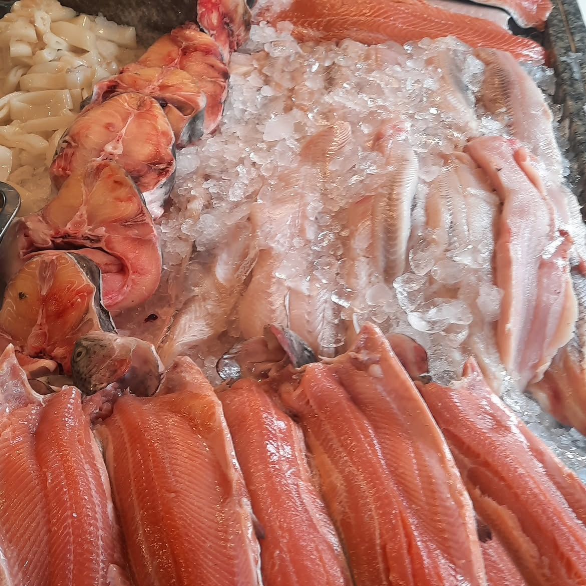 Surtido de mariscos crudos y patas de cangrejo dispuestos sobre hielo en un mostrador de mercado.