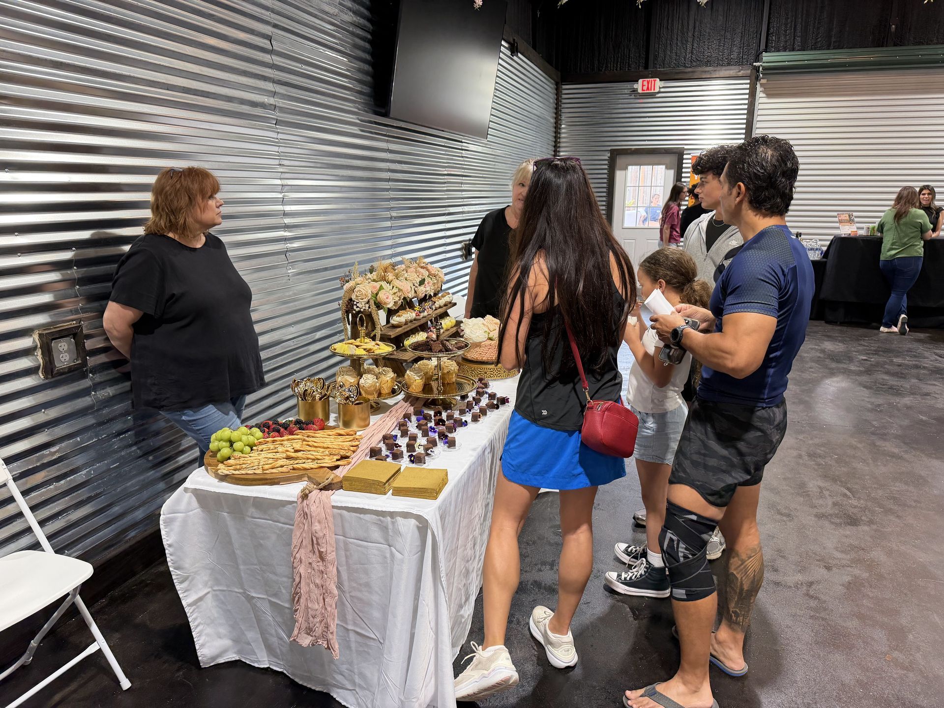 People browsing a table of assorted snacks at an indoor event.