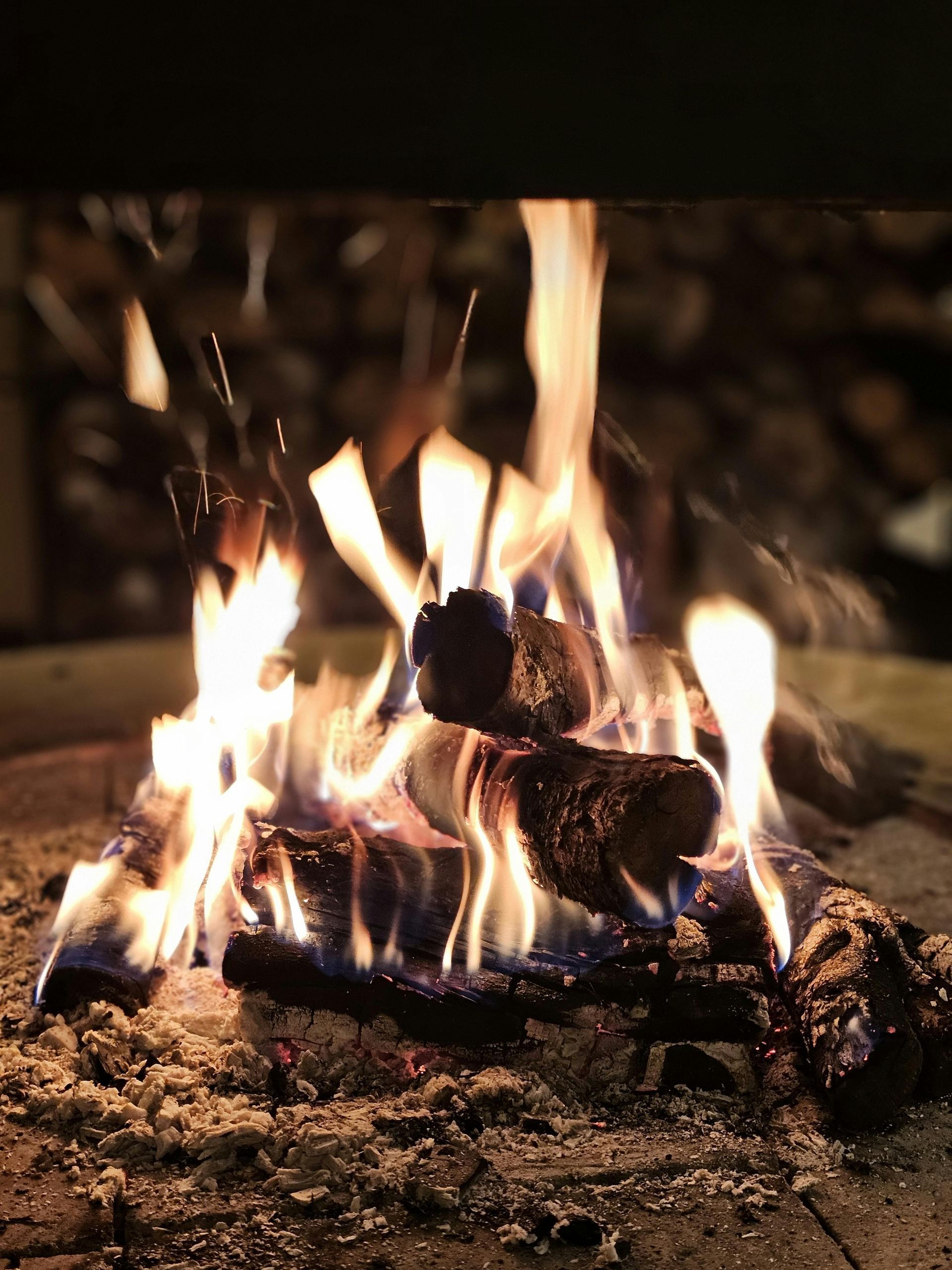 Burning logs in a fireplace with bright orange flames and glowing embers