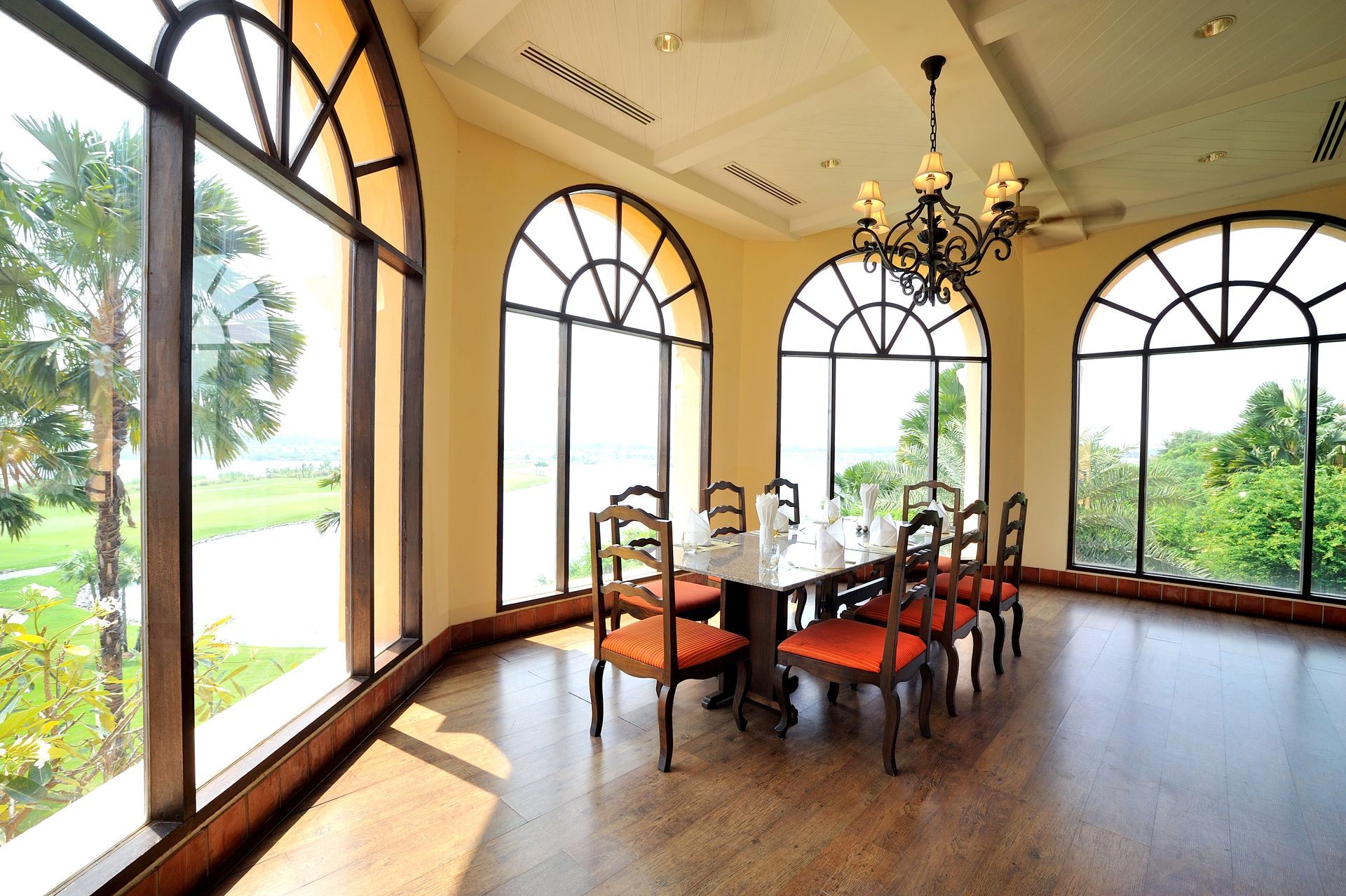 A bright dining room featuring a rectangular wooden table with six chairs upholstered in red fabric. A bright dining room featuring a rectangular wooden table with six chairs upholstered in red fabric.